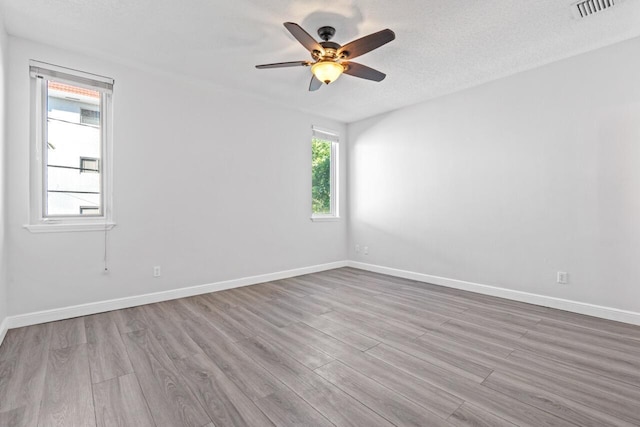 spare room featuring a textured ceiling, light hardwood / wood-style floors, and ceiling fan