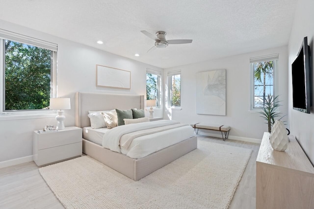 bedroom with hardwood / wood-style flooring, ceiling fan, and multiple windows