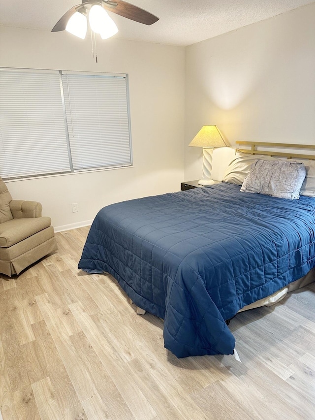 bedroom featuring ceiling fan, light wood-type flooring, and a textured ceiling