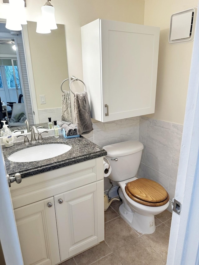 bathroom with vanity, tile patterned floors, ceiling fan, toilet, and tile walls