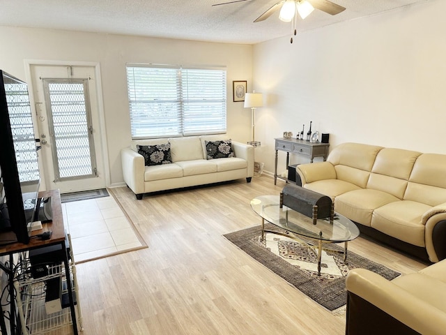 living room featuring ceiling fan, light hardwood / wood-style floors, and a textured ceiling