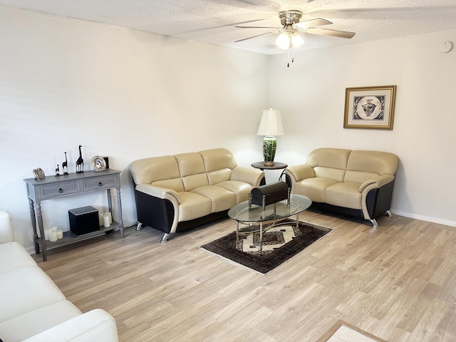 living room with ceiling fan, a textured ceiling, and light hardwood / wood-style flooring