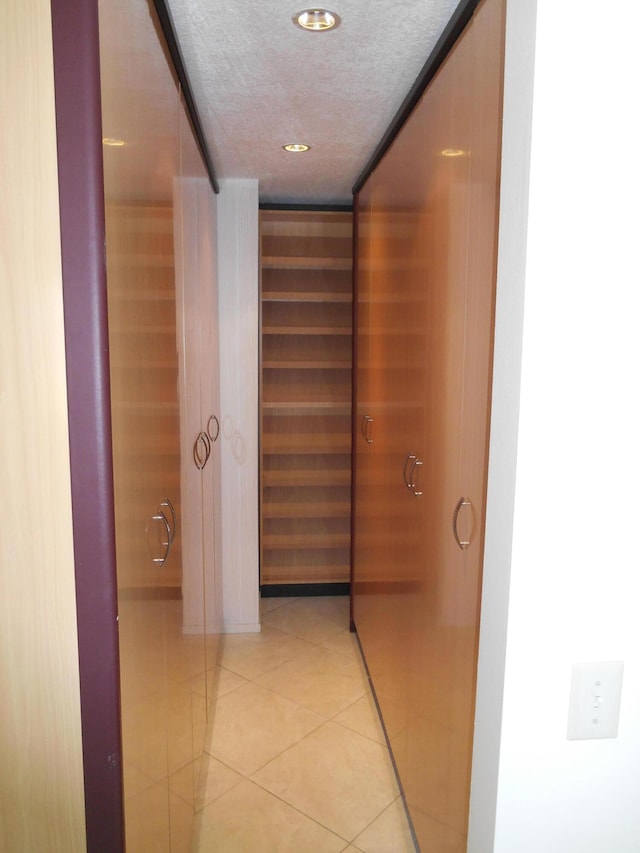 hall featuring light tile patterned flooring and a textured ceiling