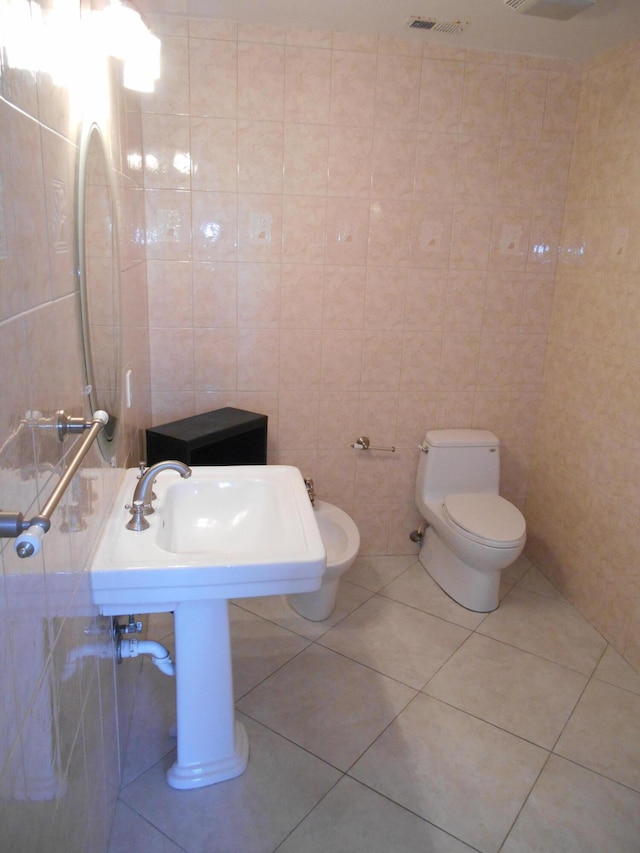 bathroom with sink, tile patterned flooring, tile walls, and toilet