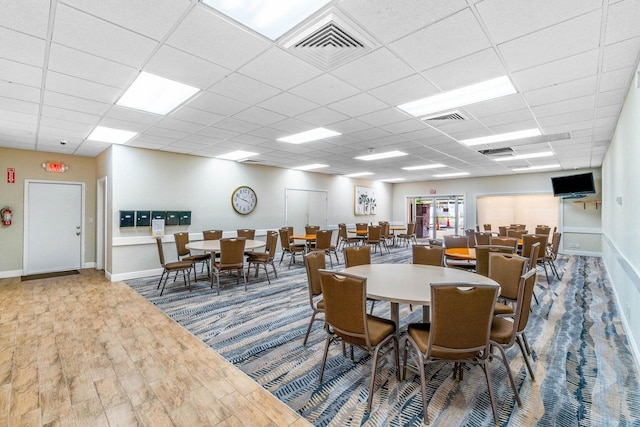 dining space with hardwood / wood-style flooring and a drop ceiling