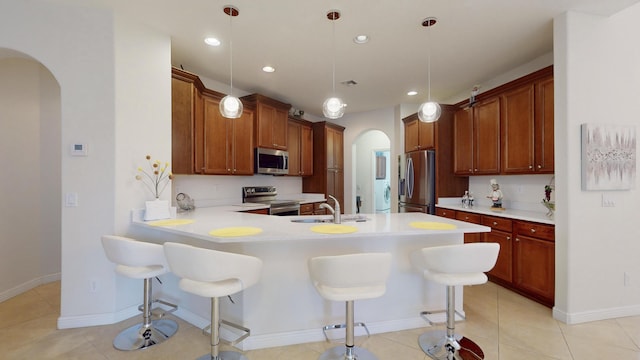 kitchen with stainless steel appliances, sink, hanging light fixtures, a breakfast bar area, and light tile patterned flooring