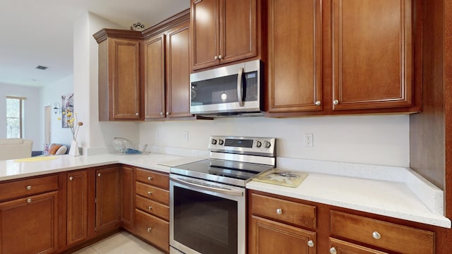 kitchen with stainless steel appliances, light stone counters, and light tile patterned flooring