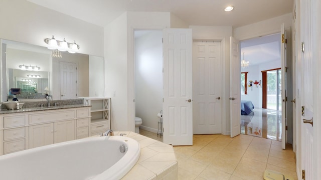 bathroom with tile patterned floors, vanity, toilet, and tiled tub