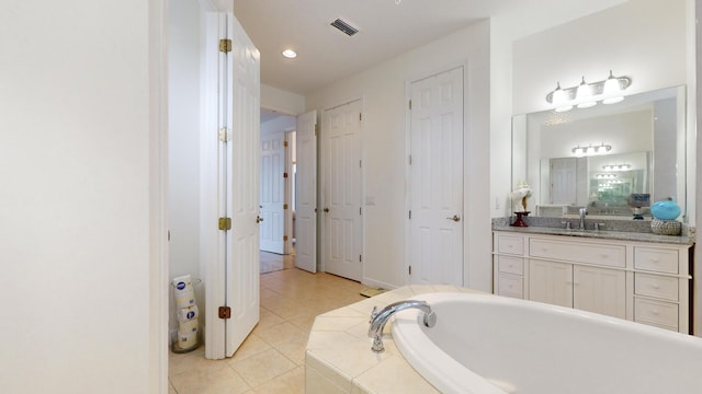 bathroom featuring tile patterned flooring, vanity, and tiled tub