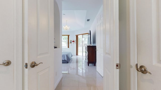 hallway featuring a notable chandelier and light tile patterned floors