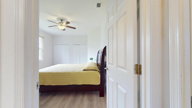 bedroom with multiple closets, ceiling fan, and light hardwood / wood-style flooring