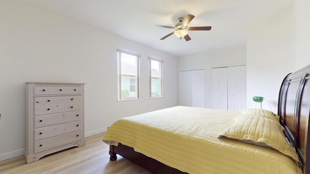 bedroom featuring multiple closets, ceiling fan, and light hardwood / wood-style flooring