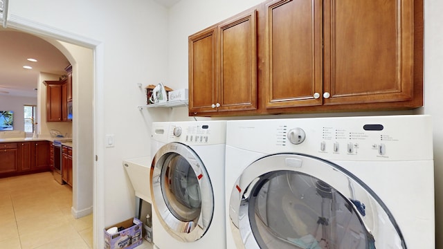 washroom featuring cabinets, light tile patterned floors, and washing machine and clothes dryer