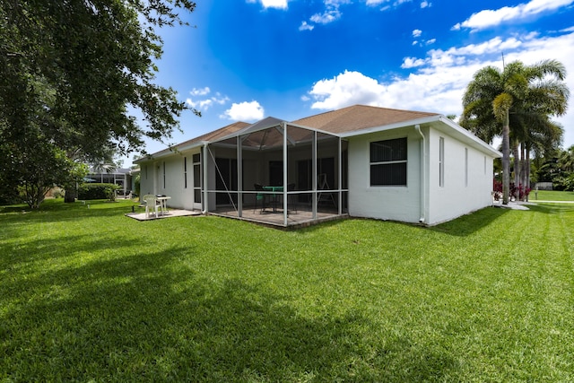 back of property featuring a patio, glass enclosure, and a lawn