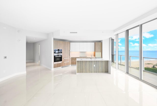 kitchen featuring white cabinets, plenty of natural light, a water view, and a beach view