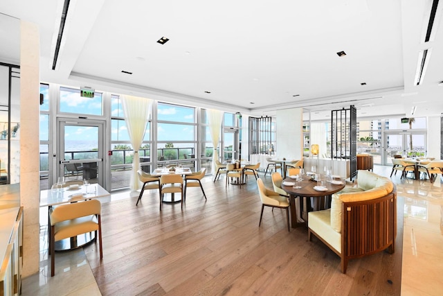 dining area featuring floor to ceiling windows, light hardwood / wood-style floors, a raised ceiling, and plenty of natural light