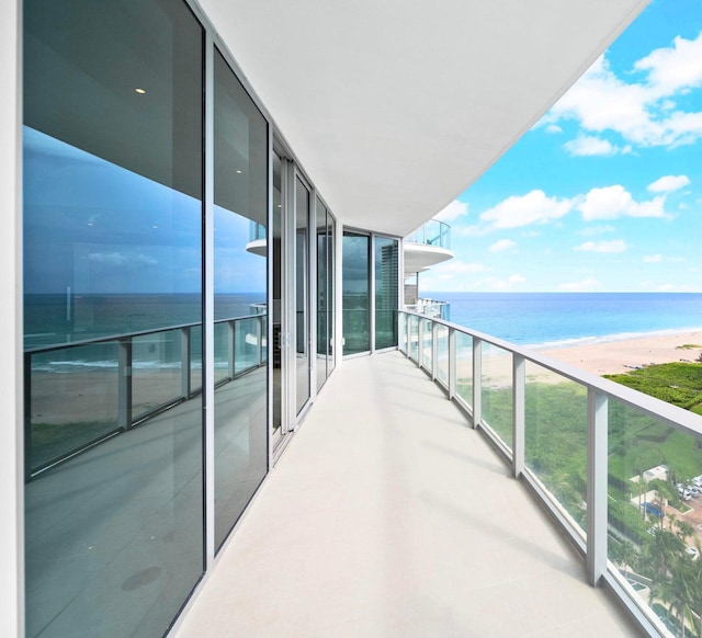 balcony with a water view and a view of the beach