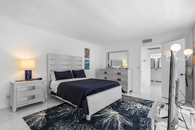 bedroom featuring ensuite bath and a textured ceiling