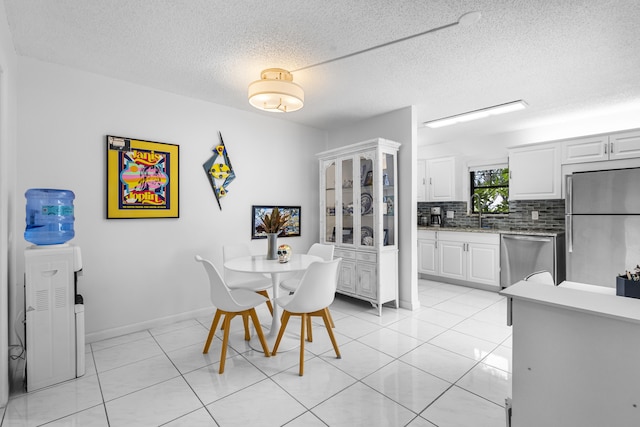 tiled dining room featuring a textured ceiling and sink