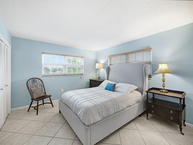 bedroom featuring a textured ceiling, a closet, and light tile patterned flooring