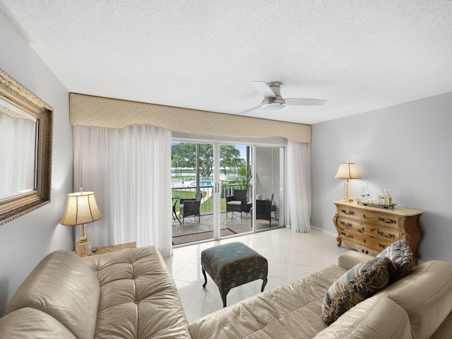 living room featuring ceiling fan, light tile patterned floors, and a textured ceiling