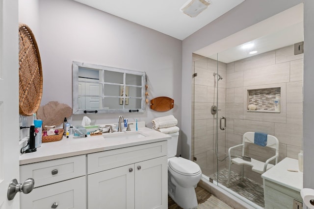 bathroom with hardwood / wood-style floors, vanity, an enclosed shower, and toilet