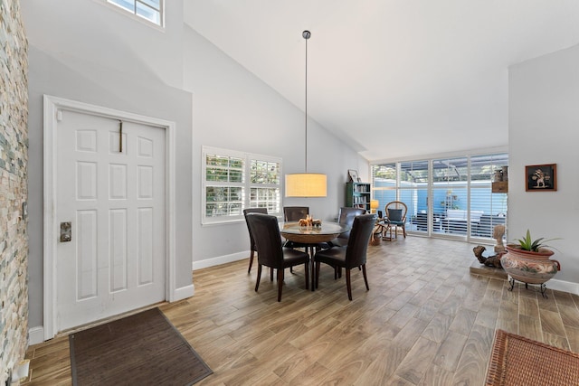 dining area with a healthy amount of sunlight, high vaulted ceiling, and light hardwood / wood-style flooring