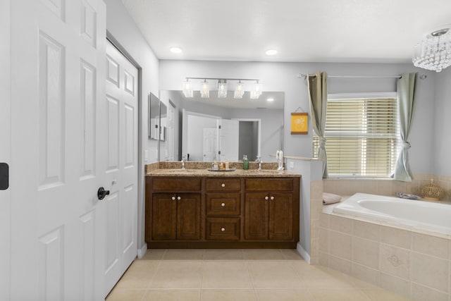 bathroom with tile patterned floors, tiled tub, vanity, and a notable chandelier