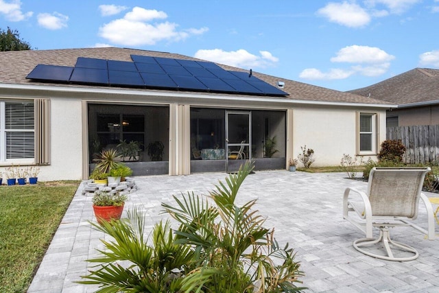 back of house featuring solar panels, a patio area, and a sunroom