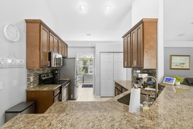 kitchen featuring decorative backsplash, light tile patterned floors, stainless steel appliances, and sink