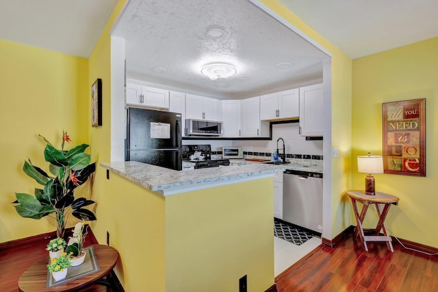 kitchen featuring dark hardwood / wood-style floors, white cabinetry, kitchen peninsula, and appliances with stainless steel finishes