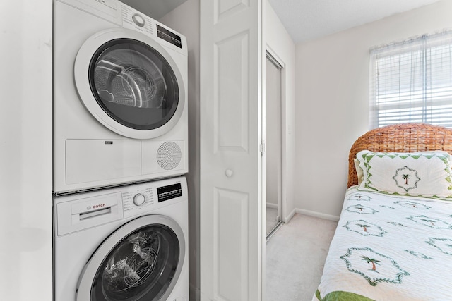 clothes washing area featuring light colored carpet and stacked washer and clothes dryer