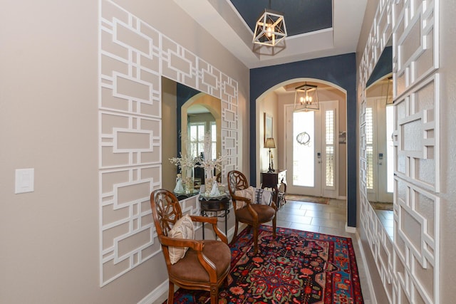 foyer with a chandelier, a raised ceiling, and tile patterned floors