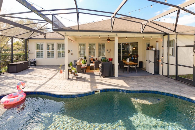 back of house featuring glass enclosure, ceiling fan, and a patio area