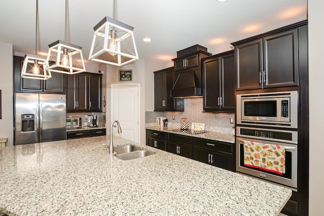 kitchen featuring light stone counters, custom range hood, stainless steel appliances, sink, and pendant lighting