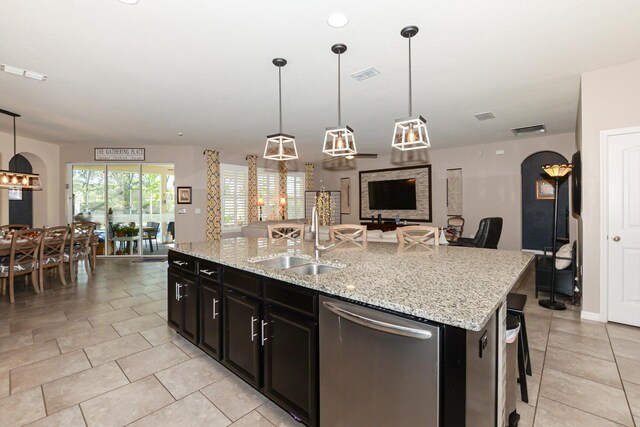 kitchen with a center island with sink, hanging light fixtures, sink, stainless steel dishwasher, and a breakfast bar area