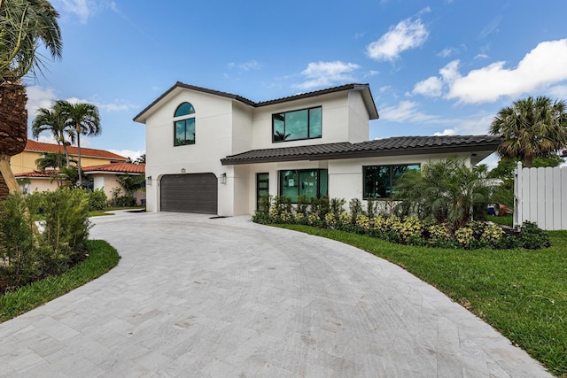 mediterranean / spanish-style home featuring a garage and a front lawn