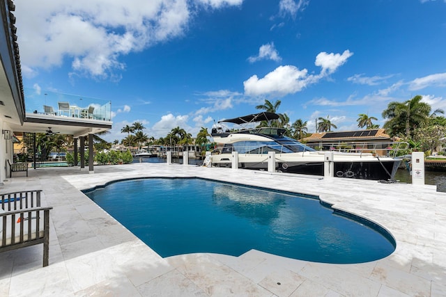 view of swimming pool featuring a water view, a patio area, ceiling fan, and a dock