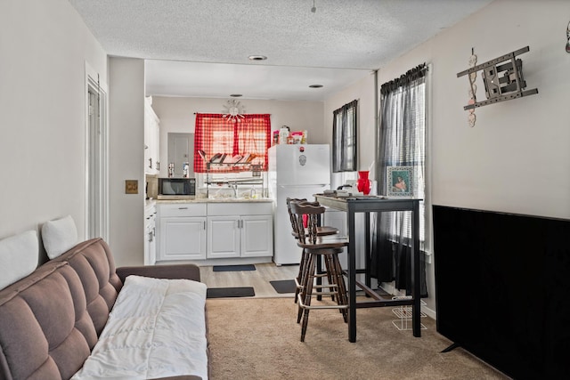 dining area with a healthy amount of sunlight, light colored carpet, and a textured ceiling