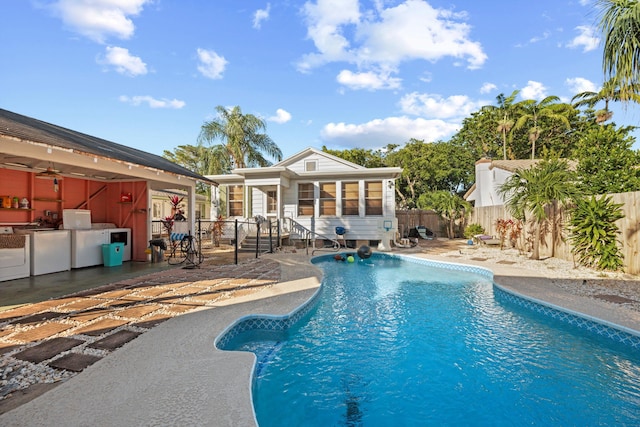 view of swimming pool with a sunroom, a patio area, and washer / clothes dryer