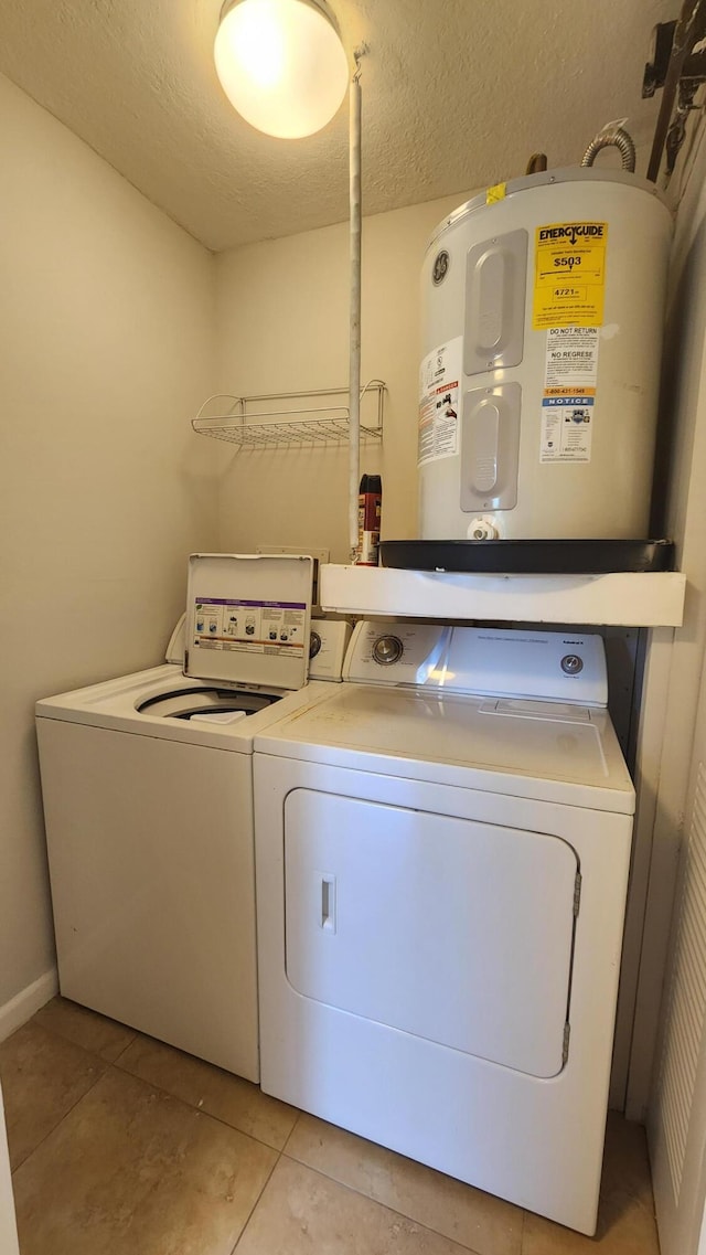 laundry area featuring washer and dryer, light tile patterned floors, a textured ceiling, and water heater