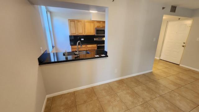 kitchen featuring backsplash, stainless steel appliances, sink, light tile patterned floors, and light brown cabinets