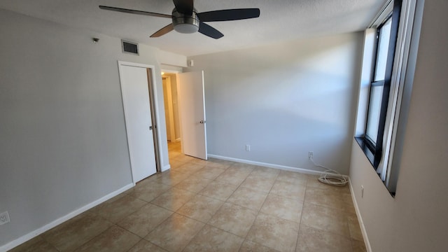 tiled empty room featuring a textured ceiling, a wealth of natural light, and ceiling fan