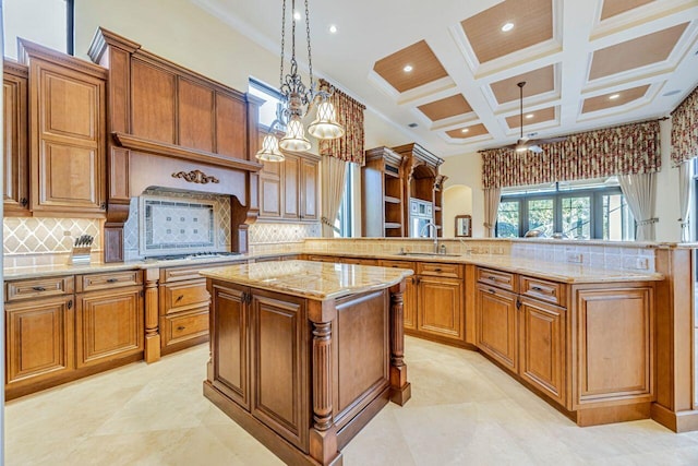 kitchen with kitchen peninsula, tasteful backsplash, sink, decorative light fixtures, and a kitchen island