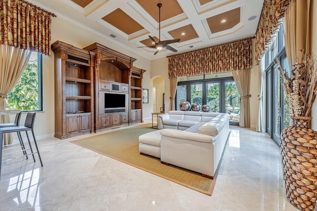 living room with ceiling fan, a high ceiling, coffered ceiling, beamed ceiling, and ornamental molding