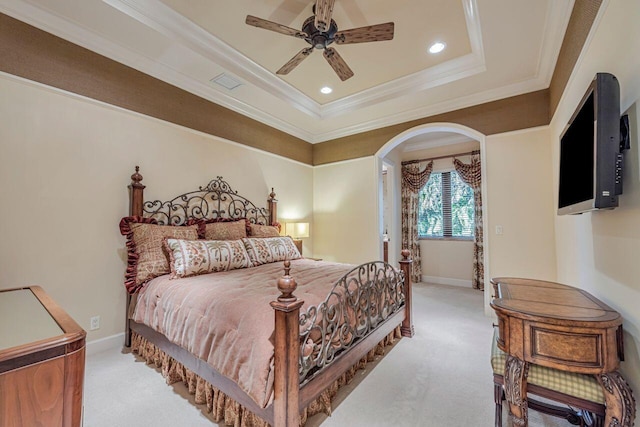 bedroom featuring ceiling fan, crown molding, light carpet, and a tray ceiling