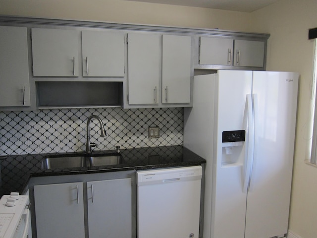 kitchen featuring gray cabinetry, white appliances, dark stone counters, sink, and tasteful backsplash