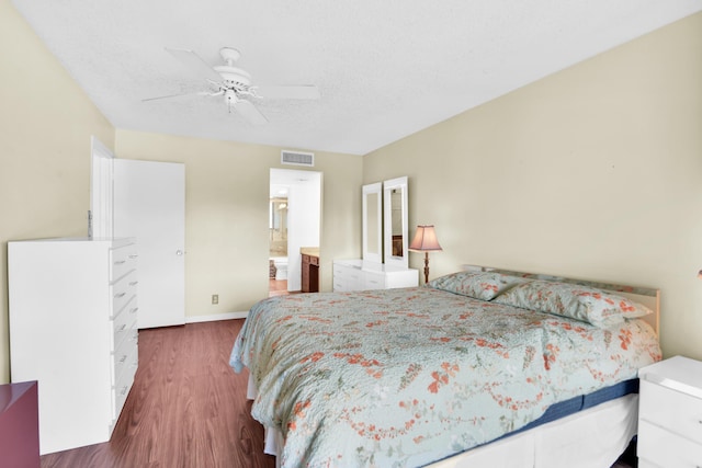 bedroom with connected bathroom, ceiling fan, dark wood-type flooring, and a textured ceiling