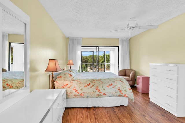 bedroom with access to outside, ceiling fan, hardwood / wood-style floors, and a textured ceiling