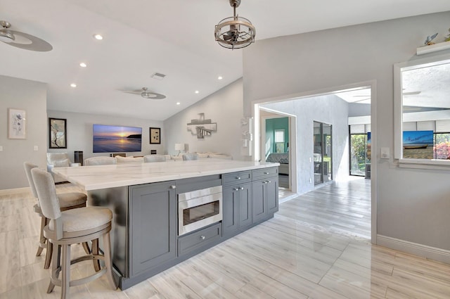 kitchen with ceiling fan, gray cabinets, light stone counters, and lofted ceiling